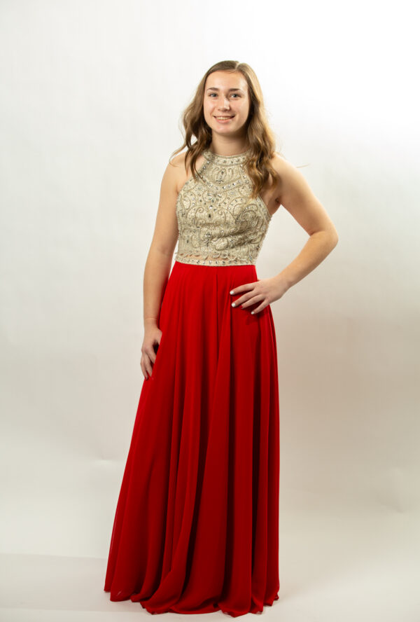 Model wears dress with red skirt and gold top