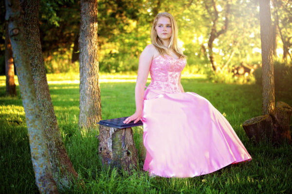 model in pink dress sits on bench