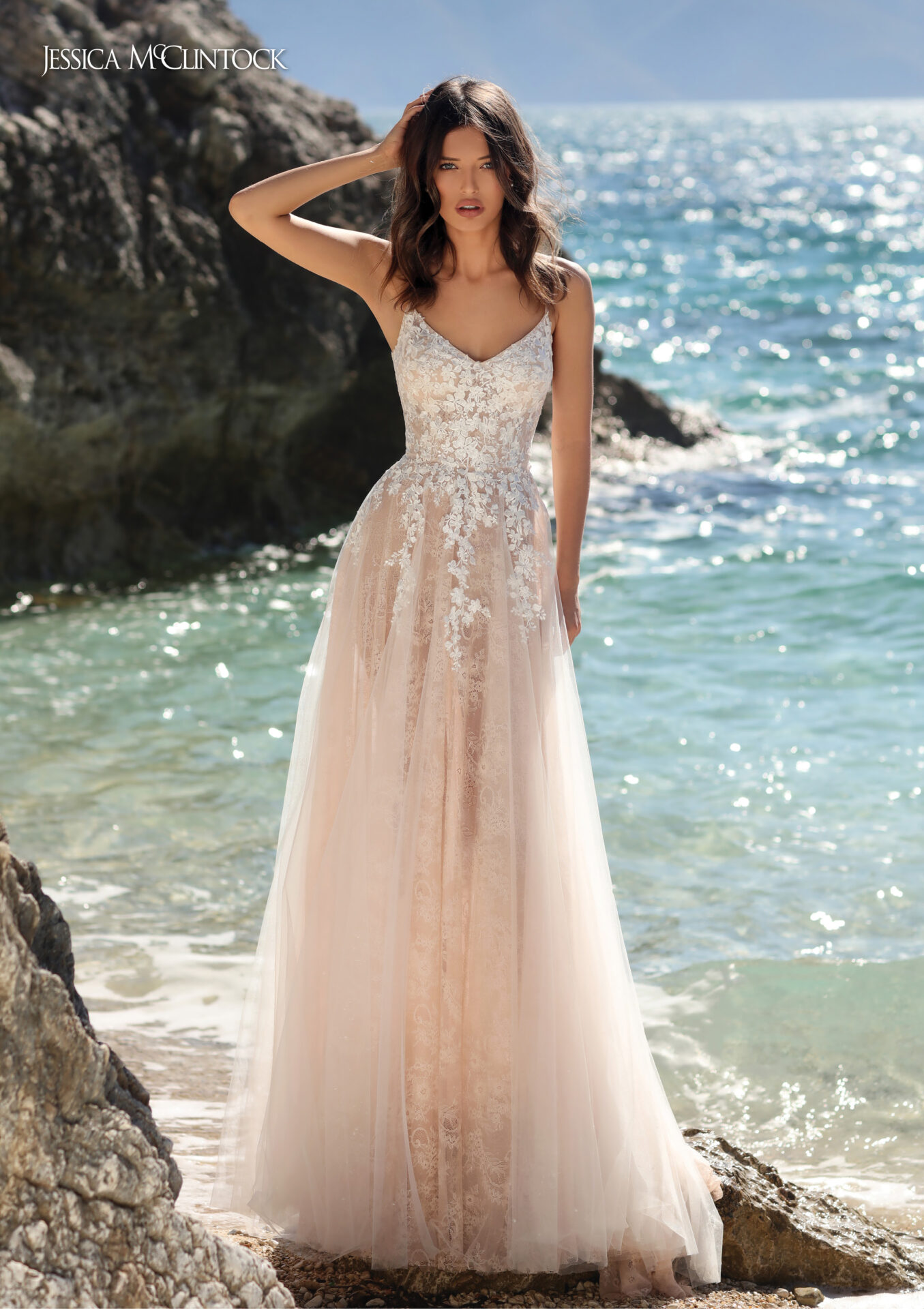 Woman in bridal gown stands on beach.